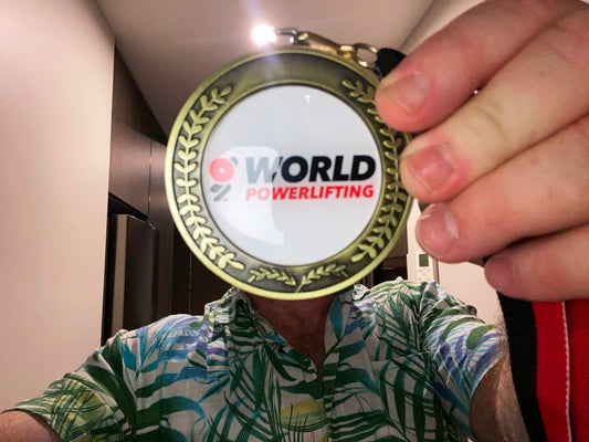 Paul proudly holding his gold medal from the 2024 Asia Pacific Championships, symbolising his triumph and preparation on the road to the World Powerlifting Championships.