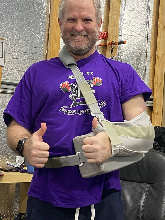 Paul in his sexy post shoulder sling, giving thumbs up signs, whilst wearing a purple Castle FY t-shirt.